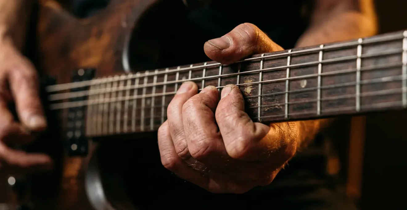 Close-up of a guitarist's fingers executing an expressive string bend on electric guitar neck with dramatic lighting