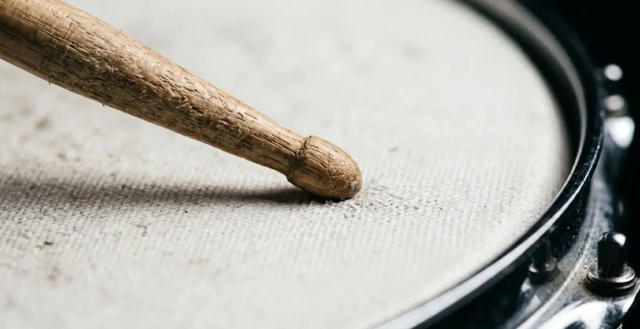 Extreme close-up of drumstick tip making contact with drum surface showing texture and precise timing