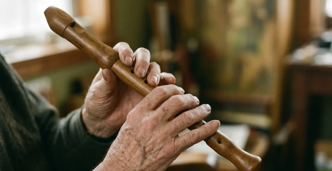 Weathered elderly hands gently holding a traditional wooden folk instrument