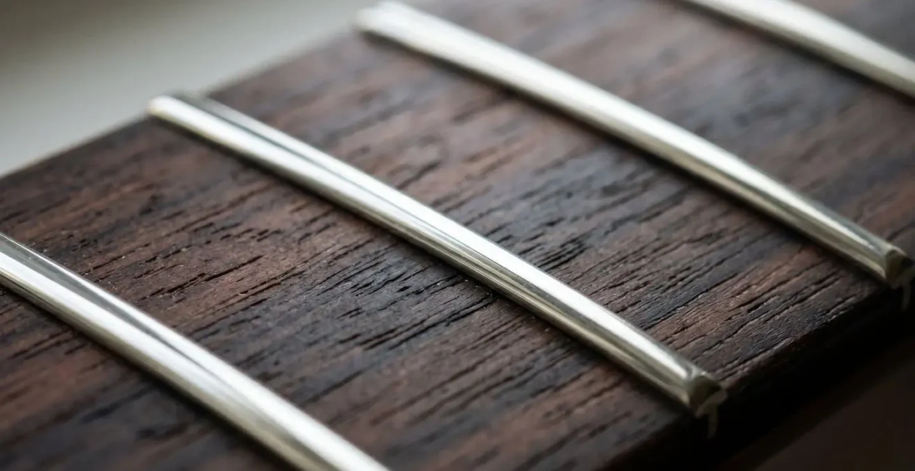 Extreme close-up macro photograph showing mirror-polished guitar frets with tactile texture detail