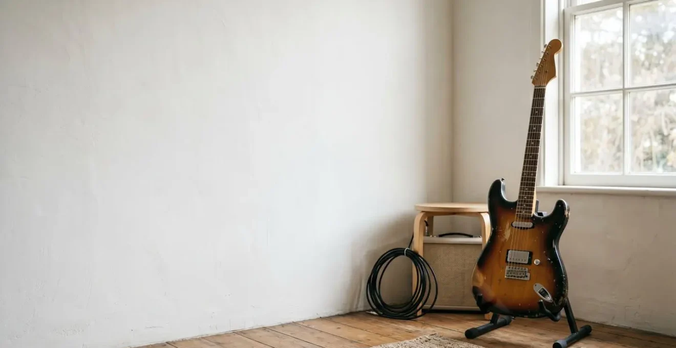 Environmental minimalist photograph showing one well-worn guitar in a clean practice space with natural lighting